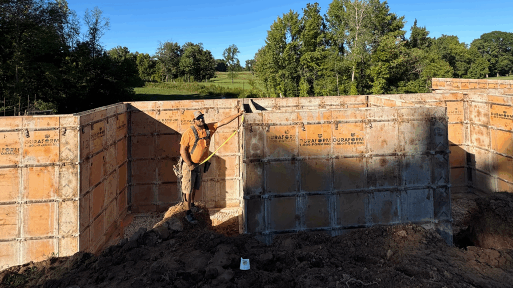 Construction worker measuring foundation walls.